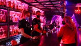 Una clienta y dos camareros con mascarilla en una discoteca / EUROPA PRESS