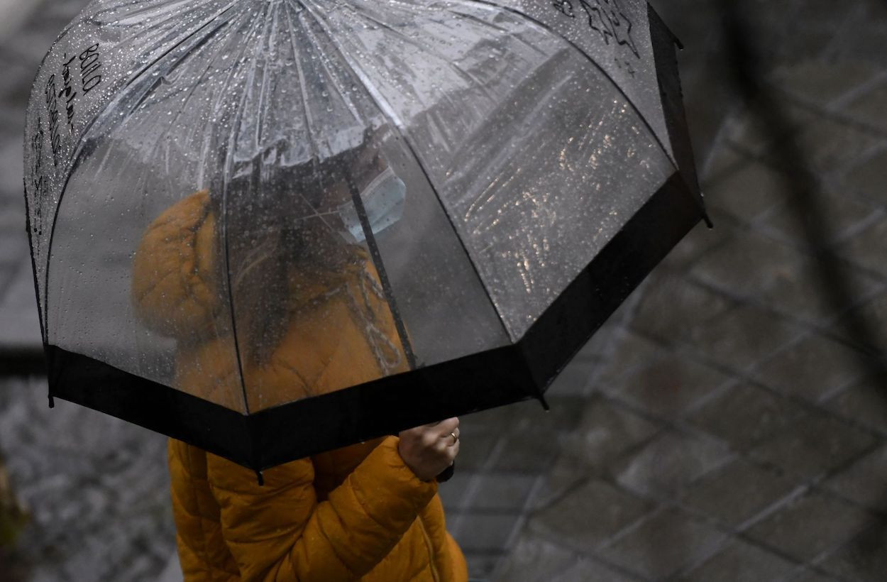Una mujer con paraguas y mascarilla en un día de lluvia / EUROPA PRESS