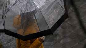 Una mujer con paraguas y mascarilla en un día de lluvia / EUROPA PRESS