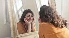 Una mujer se mira en el espejo con una expresión de felicidad /QUIRÓNSALUD