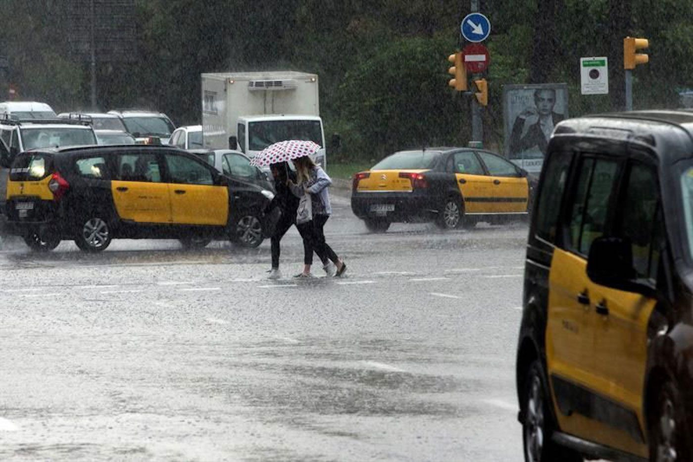 Dos mujeres cruzan una calle durante un episodio de lluvias y frío posterior a días con clima veraniego en Barcelona / EFE