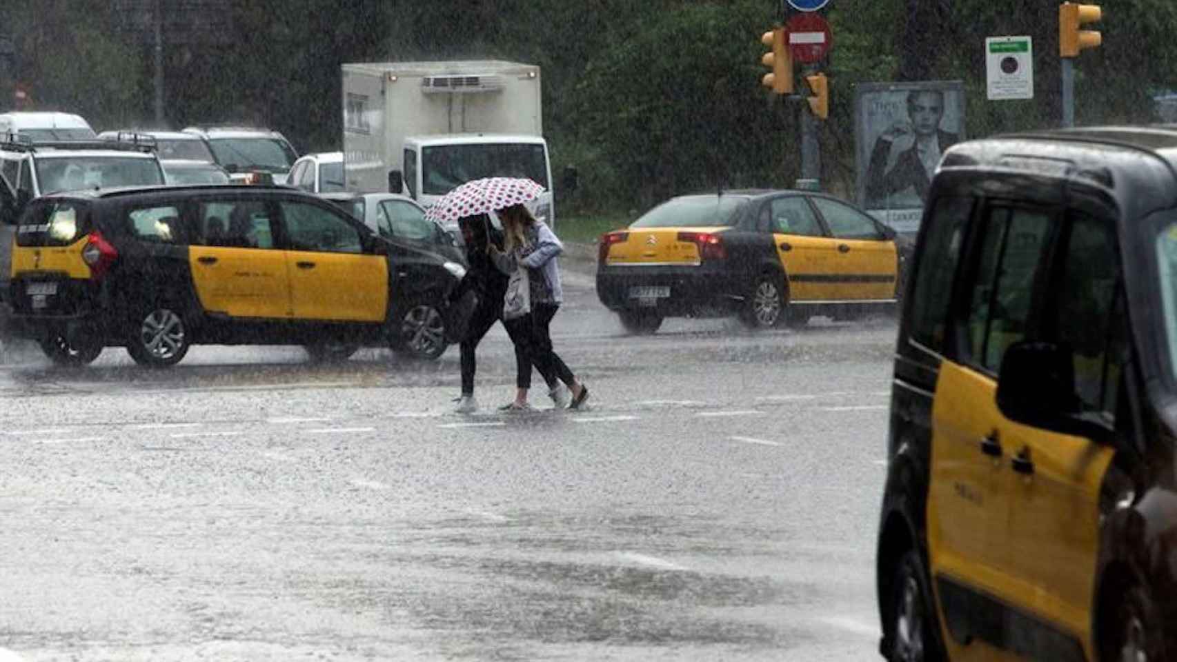Dos mujeres cruzan una calle durante un episodio de lluvias y frío posterior a días con clima veraniego en Barcelona / EFE