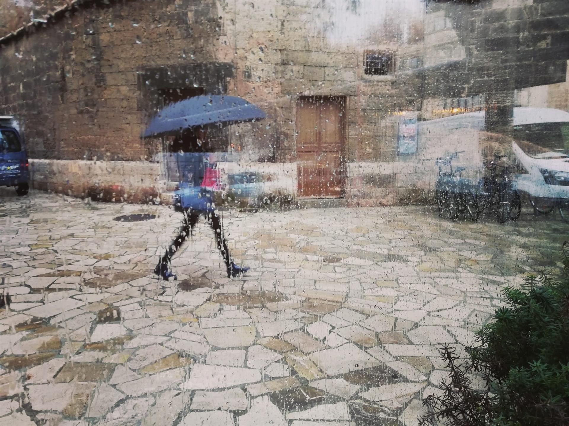 Una mujer con un paraguas, vista a través de un cristal con gotas de lluvia / EUROPA PRESS