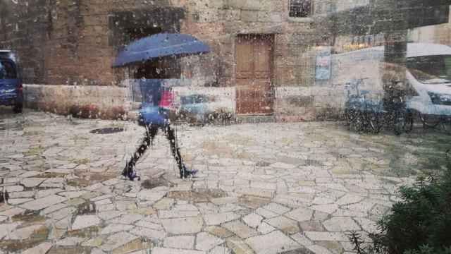 Archivo - Una mujer con un paraguas, vista a través de un cristal con gotas de lluvia. - EUROPA PRESS - Archivo