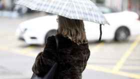 Una mujer se protege de la lluvia bajo un paraguas / EUROPA PRESS