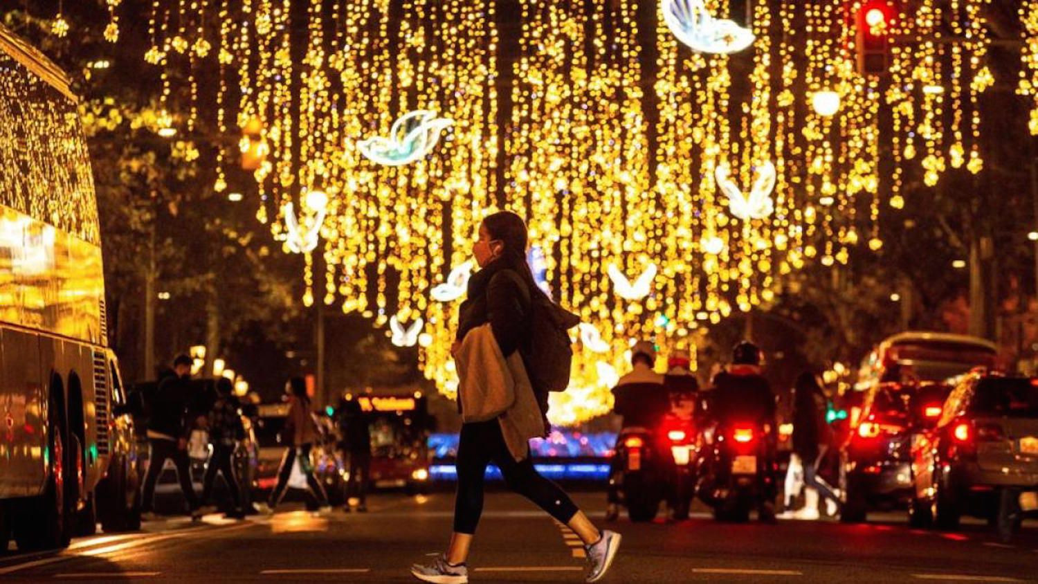 Una mujer pasea por Barcelona con las luces de Navidad encendidas / EFE