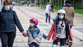 Niños y padres paseando en la calle con mascarilla durante el brote de coronavirus / EFE
