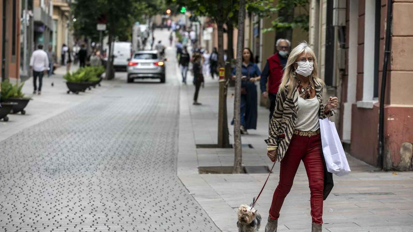 Una mujer pasea con la mascarilla puesta por la calle Major de Sarrià, uno de los barrios más acomodados de Barcelona / AYUNTAMIENTO DE BARCELONA