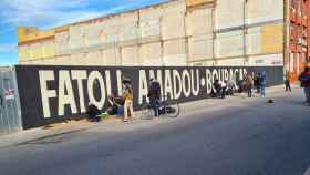 Los supervivientes de la nave quemada en Badalona hace un año pintan el mural con los nombres de los fallecidos / CEDIDA