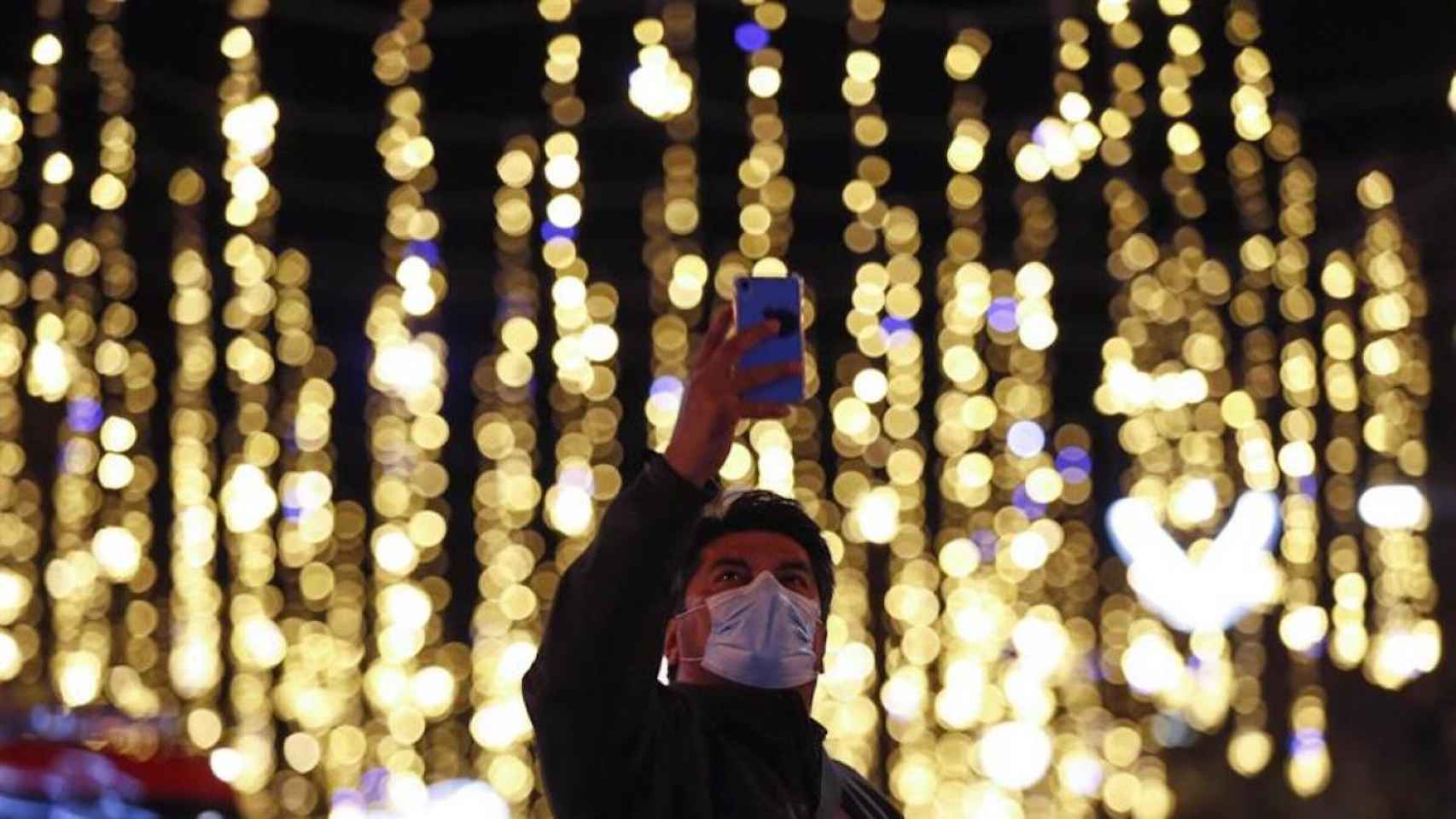 Un hombre fotografía las luces navideñas en el centro de Barcelona / EFE
