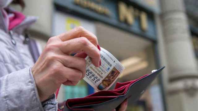 Una mujer guarda un décimo de la lotería de Navidad que acaba de comprar / EFE