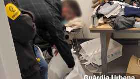 Un agente de la Guardia Urbana, comprobando las decenas de piezas de ropa robadas en el centro de Barcelona / GUARDIA URBANA