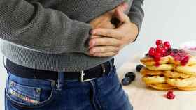 Un hombre se queja de dolor de estómago, uno de los síntomas del síndrome de intestino irritable / QUIRÓNSALUD