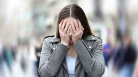 Una mujer se tapa la cara en plena calle como síntoma de depresión o ansiedad / QUIRÓNSALUD