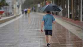 Una persona en el paseo marítimo cubierto con un paraguas / EFE
