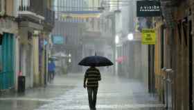 Una persona pasea por una calle cubierto con un paraguas en un día lluvioso / Natxo Francés - EFE