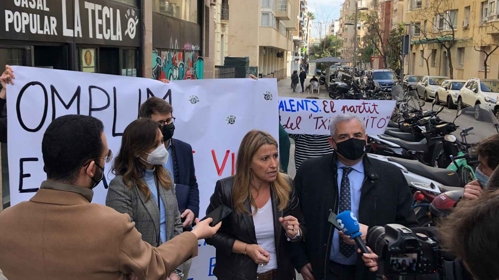 Un momento de la rueda de prensa en la calle de Madrazo con una pancarta okupa detrás / VALENTS