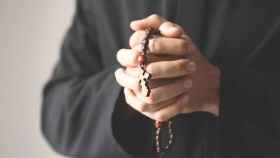 Imagen de archivo de un sacerdote sosteniendo un rosario
