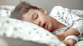 Un niño duerme en su cama: la apnea obstructiva infantil es una alteración muy común en los más pequeños / QUIRÓNSALUD