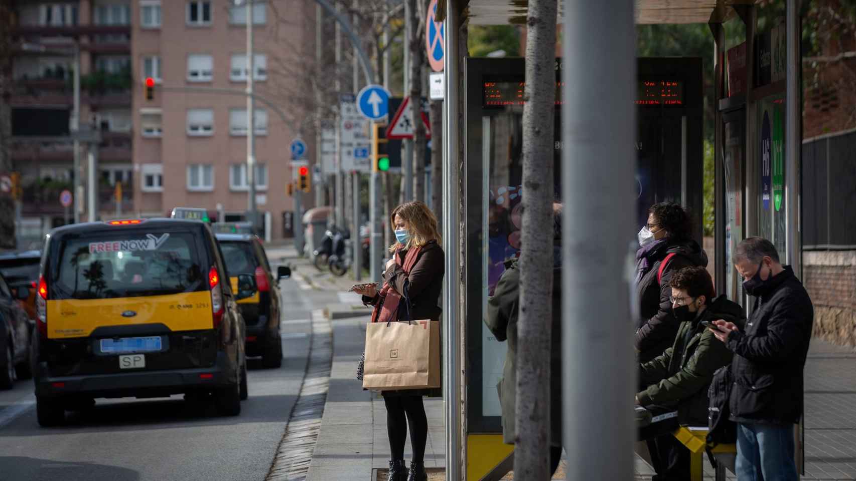 Varias personas esperan en una parada de bus de Barcelona / EUROPA PRESS