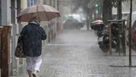 Una mujer se protege de la lluvia con un paraguas durante una alerta amarilla en Barcelona / EFE