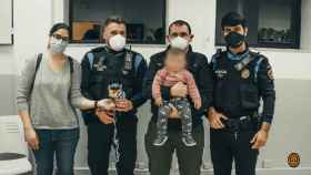 Los dos agentes que salvaron al bebé y sus padres, con la menor en brazos / POLICIA LOCAL D'ESPLUGUES DE LLOBREGAT