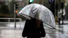 Una mujer se protege del frío y la lluvia con un paraguas / EFE