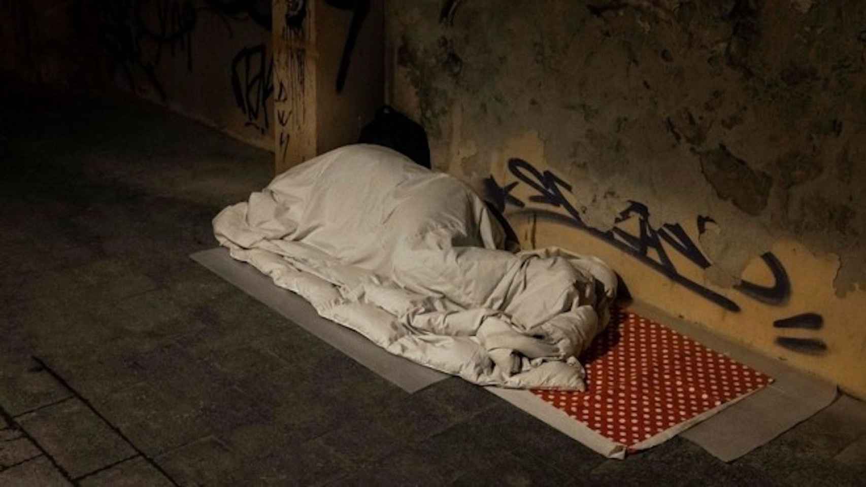 Una persona sin hogar duerme bajo un edredrón / EFE