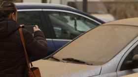 Una mujer fotografía su coche tras la lluvia de barro de la pasada semana / EFE
