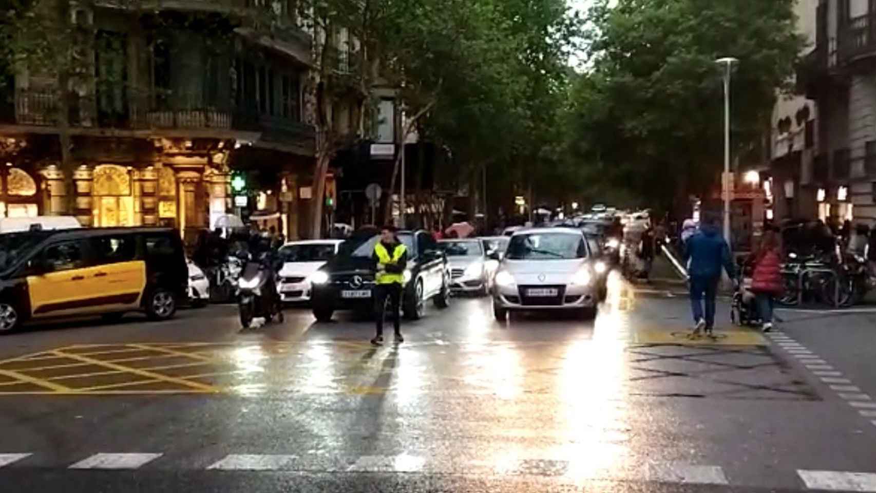 Un auxiliar delante de coches en la confluencia de rambla de Catalunya con València, en el centro de Barcelona / METRÓPOLI
