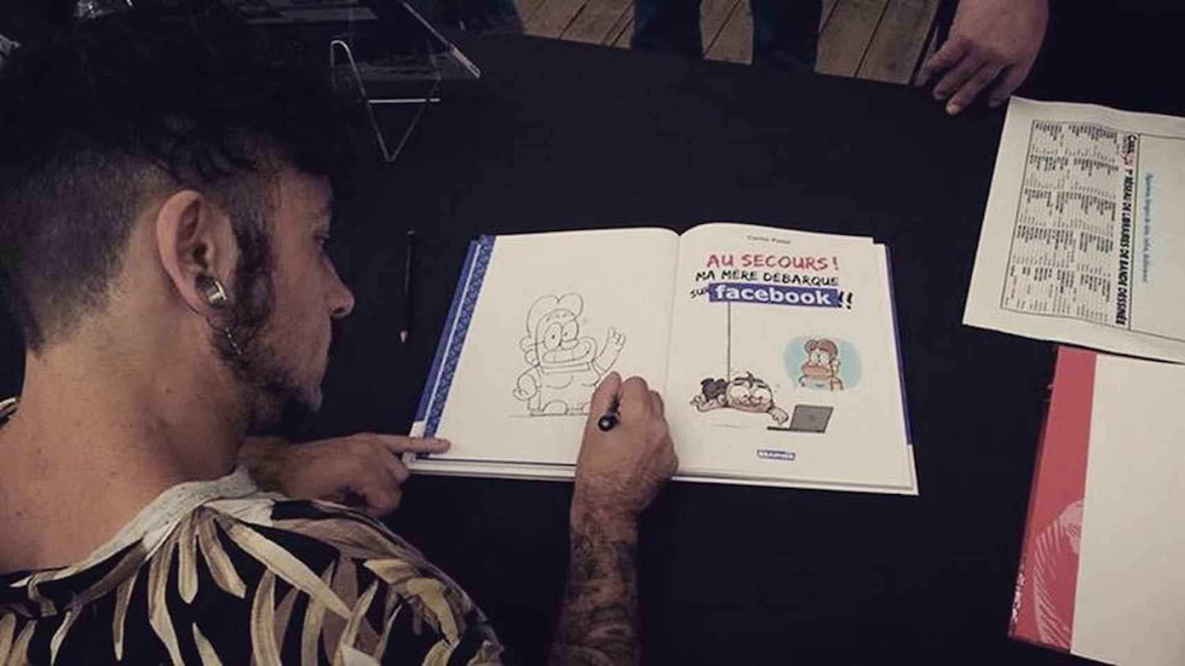 Carles Ponsí realiza un dibujo sobre un libro en una imagen de archivo / FACEBOOK