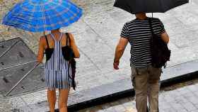 Dos personas se protegen de la lluvia de verano en Barcelona / EFE