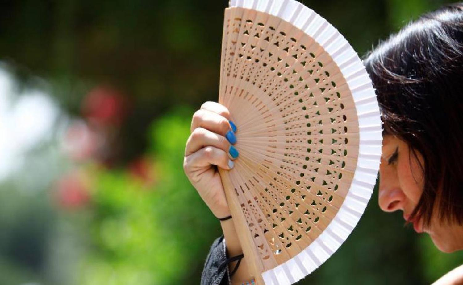 Una mujer hace pasar el calor con un abanico en una imagen de archivo / EFE