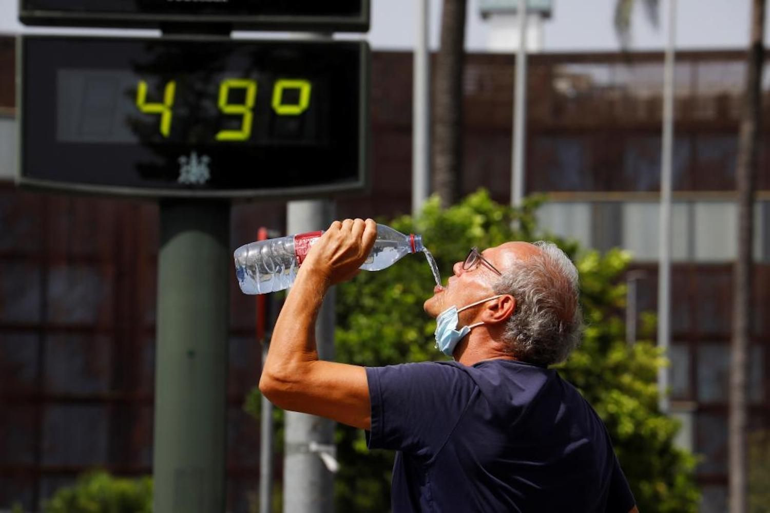 Un hombre bebe agua en plena ola de calor / EFE