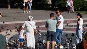 Una de las payasas junto a una niña y turistas en la plaza de Cataluña, donde también actúan / METRÓPOLI