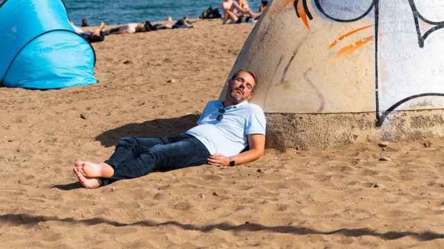 Un hombre haciendo la siesta en la Barceloneta / LUIS MIGUEL AÑÓN (MA)