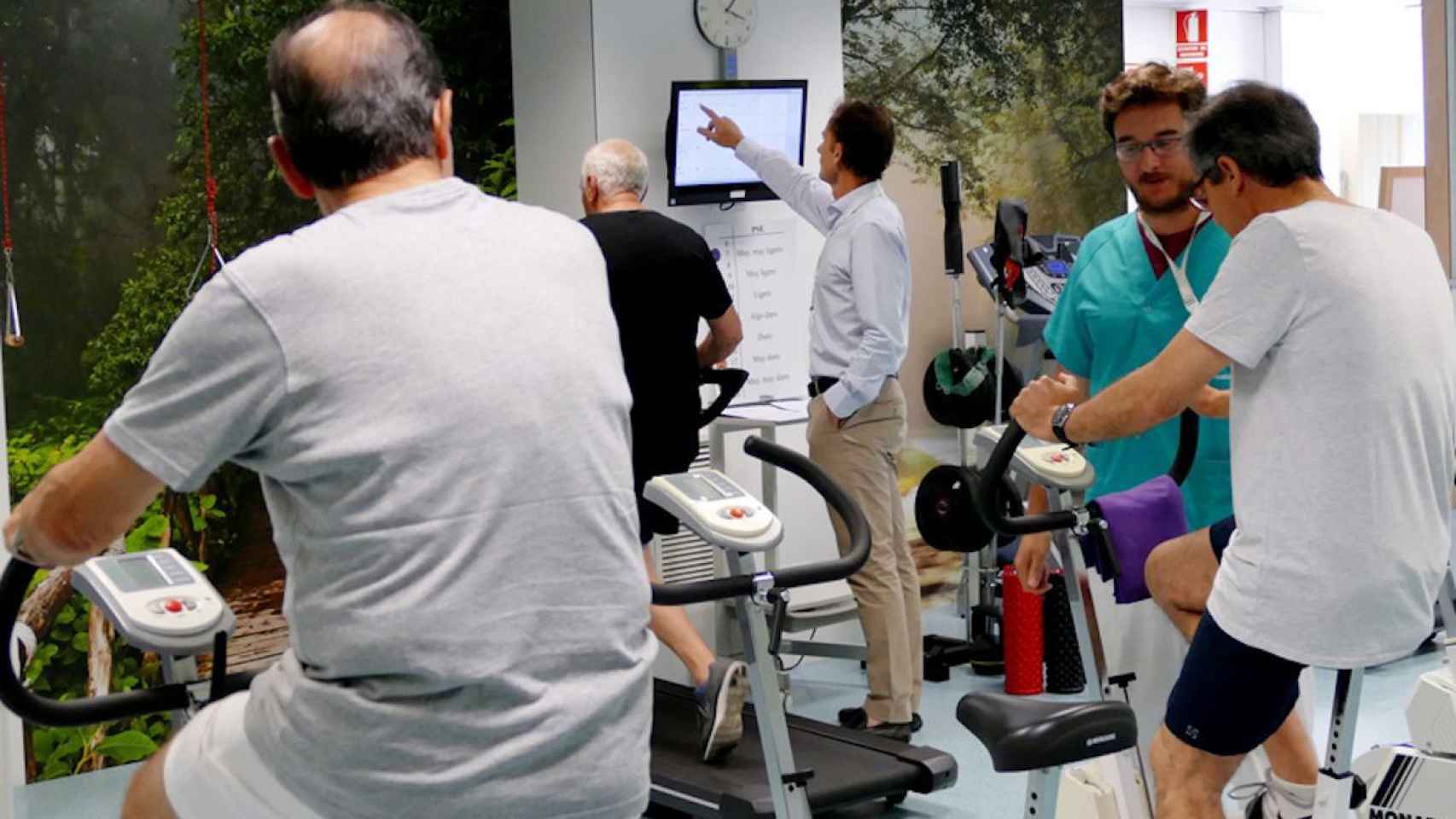Un médico controla a varios hombres mientras hacen deporte: la actividad física mejora la calidad de vida / QUIRÓNSALUD