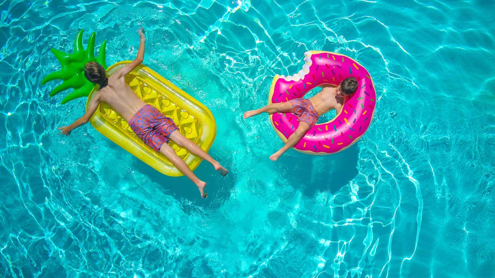Dos niños toman el sol dentro de una piscina. Hay fotoprotectores indicados para cada miembro de la familia / PX