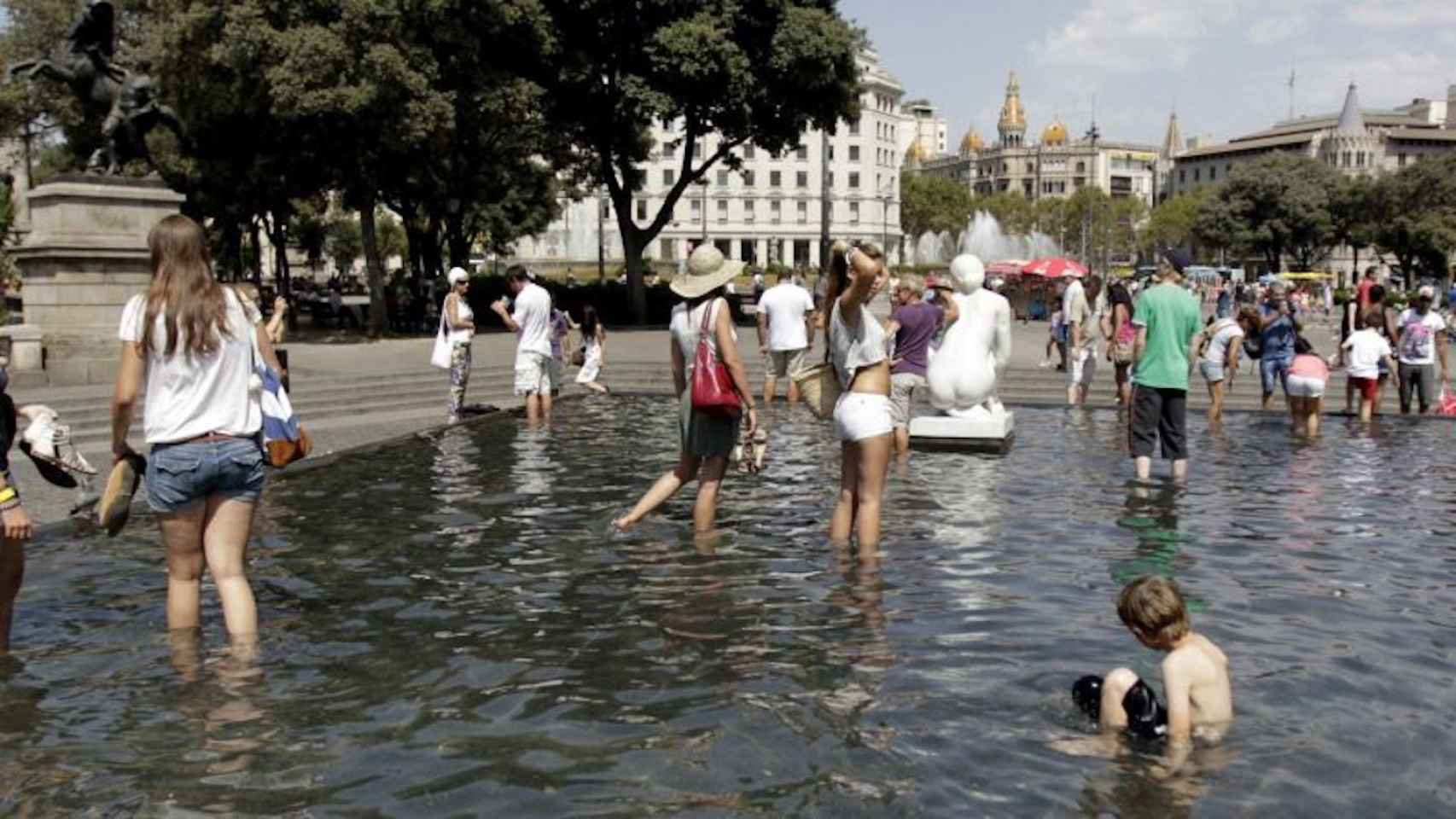 Personas refrescándose en una fuente de Barcelona en un día de aviso amarillo por altas temperaturas / EFE