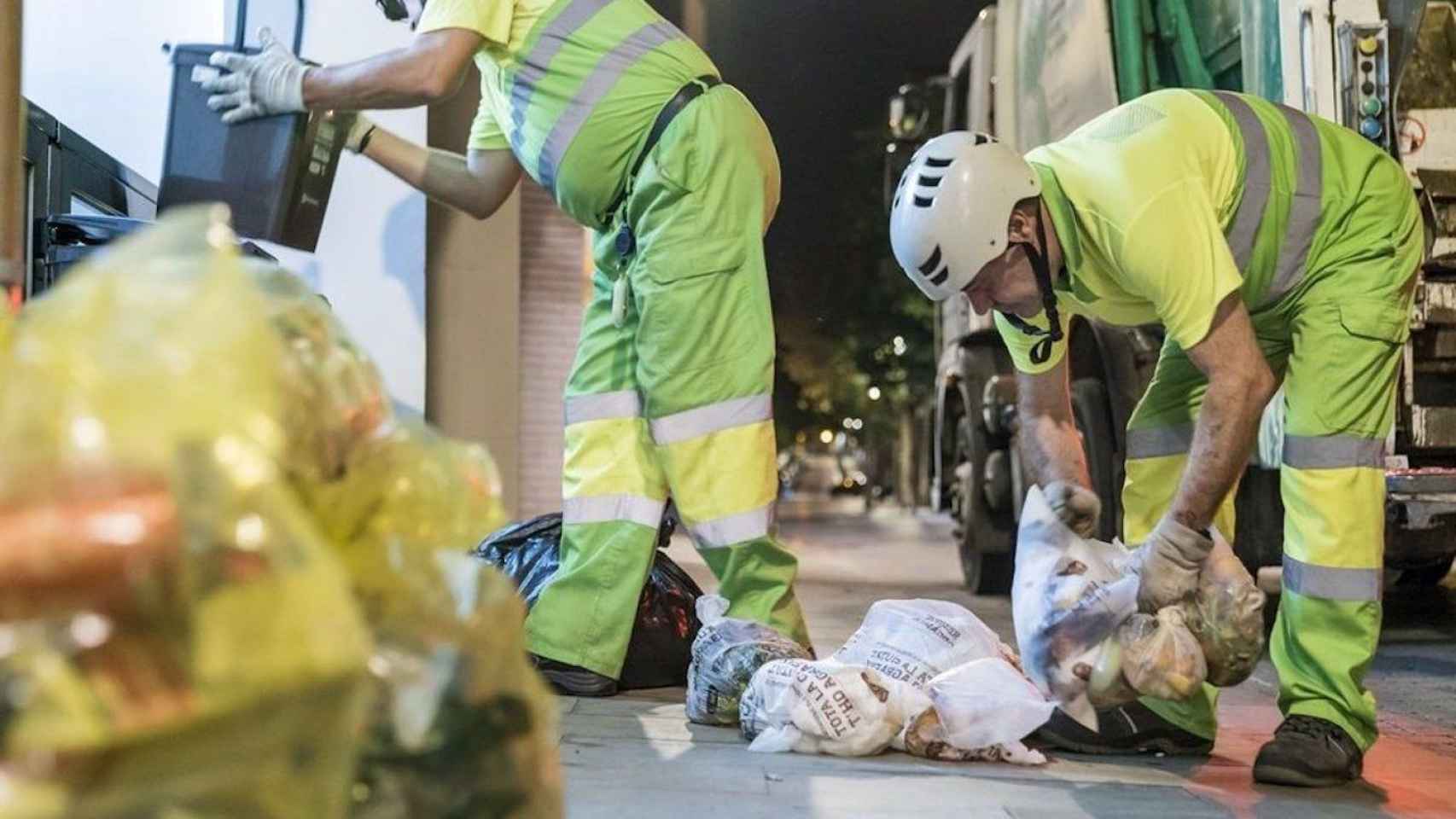 Dos empleados de la basura recogiendo unas bolsas durante la temporada de verano / AYUNTAMIENTO DE BARCELONA