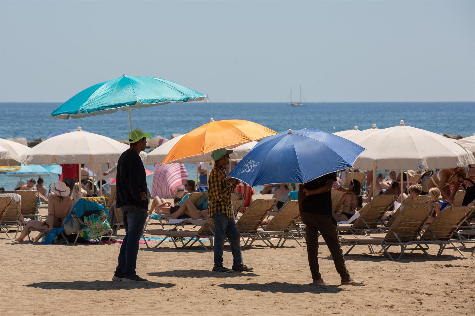 Varias personas se protegen del sol en la playa de la Barceloneta / David Zorrakino - Europa Press
