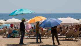 Varias personas se protegen del sol en la playa de la Barceloneta / David Zorrakino - Europa Press