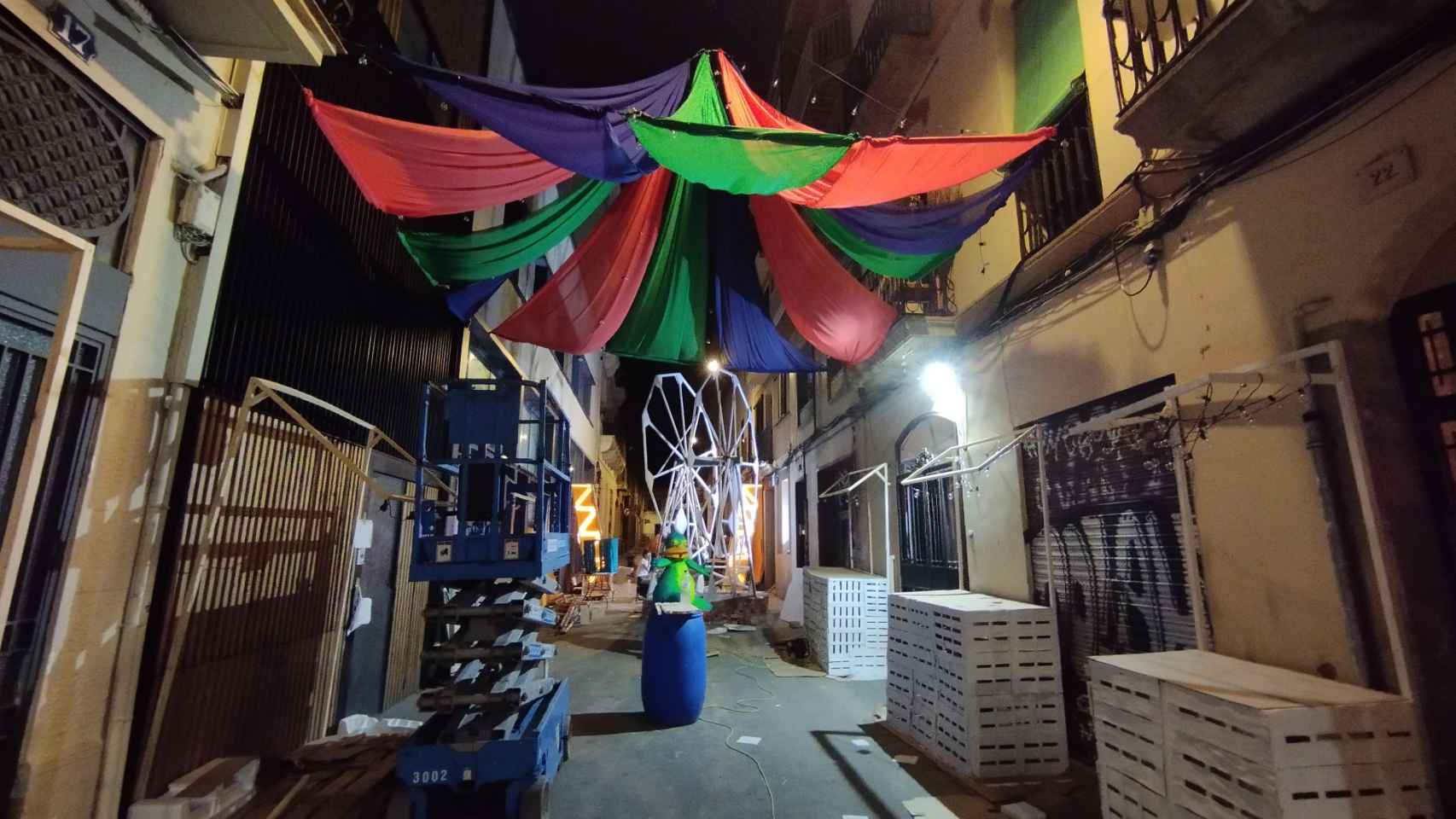 La calle Progrés este sábado por la noche durante el montaje de la decoración de un parque de atracciones / METRÓPOLI