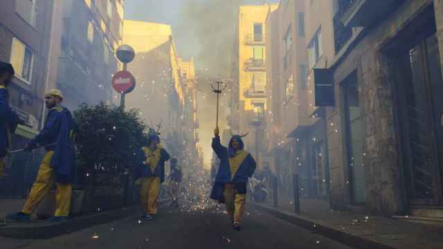 Un 'diable' salta mientras sostiene su antorcha este lunes en la Vila de Gràcia
