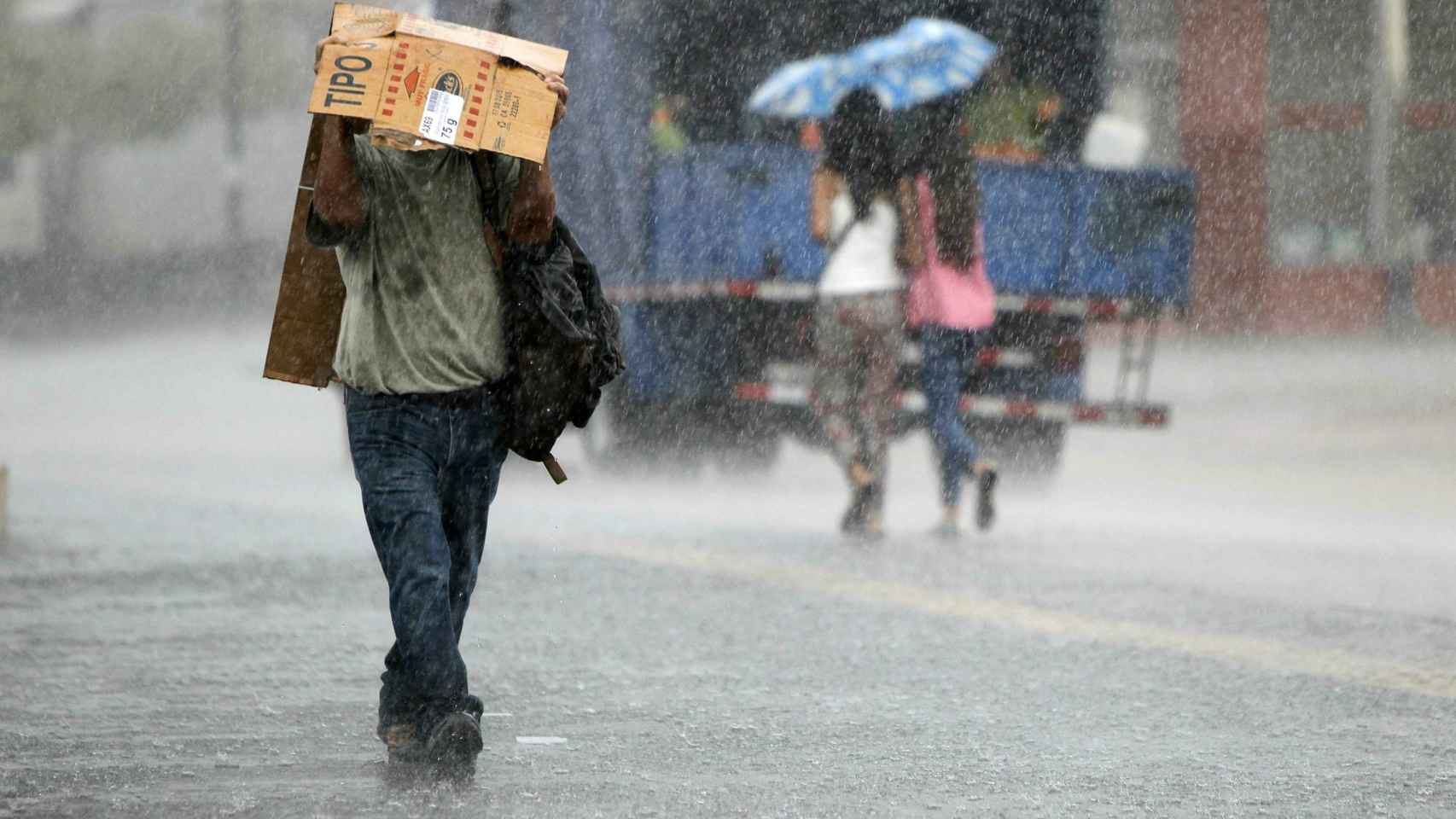 Jornada lluviosa con personas cubriéndose de las precipitaciones / EFE