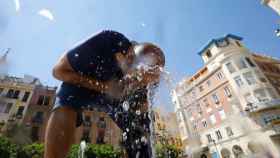 Un hombre se refresca para aliviar el caluroso verano en una fuente del centro / EFE - Salas