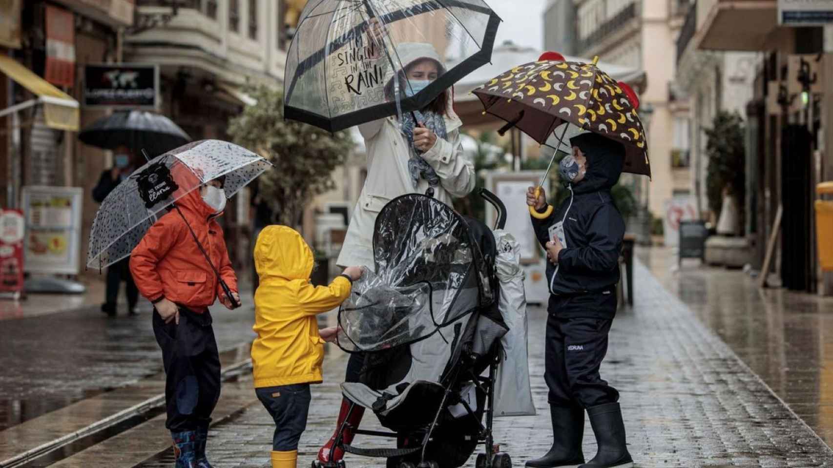 Dos personas se resguardan de un temporal de lluvia / EFE