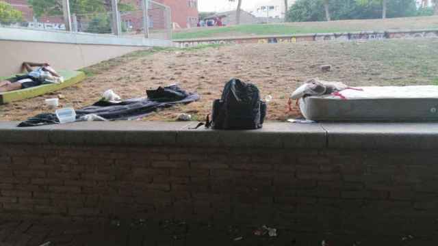 Un hombre duerme sobre el colchón en el parque de Sant Pau del Camp rodeado de basura / CEDIDA