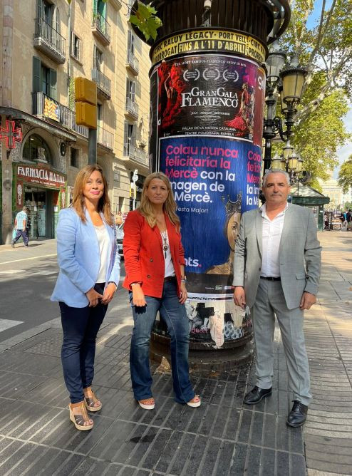 Marilén Barceló, Eva Parera y Òscar Benítez junto al cartel de la Mercè que han colgado / VALENTS 