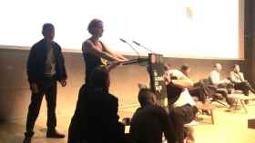 La activista en el atril en el que se ha pegado en el acto al que ha ido Colau en Barcelona / EUROPA PRESS